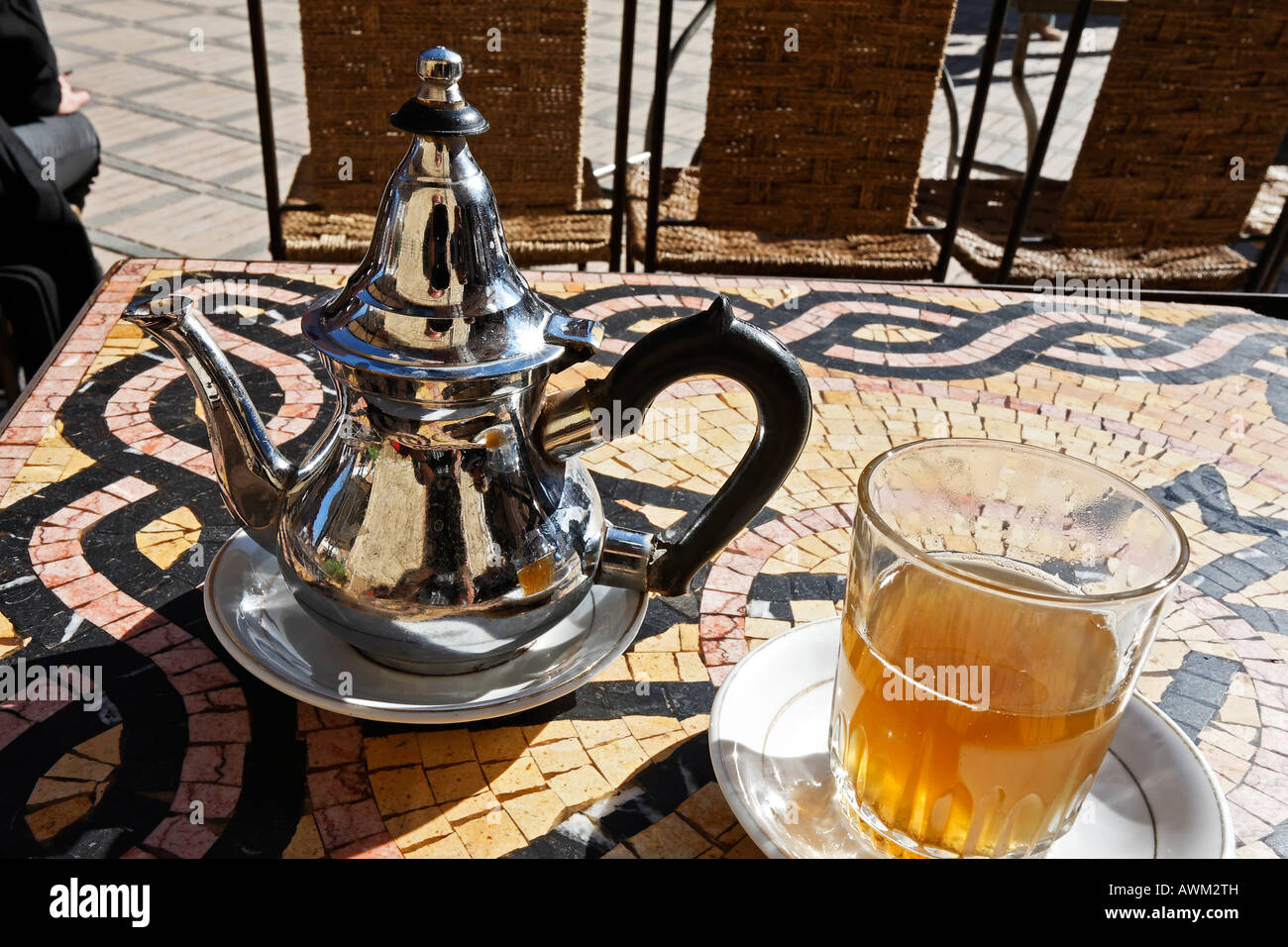 Ornate Moroccan teapot and glass on a mosaic table at a street café in