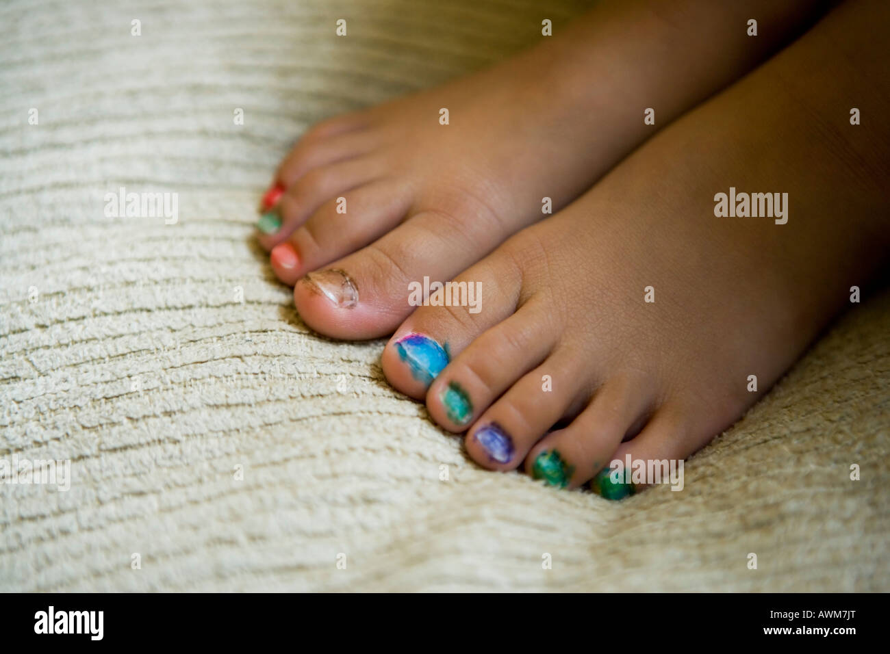 Little girl aged four years hand paints her own toenails with felt tip