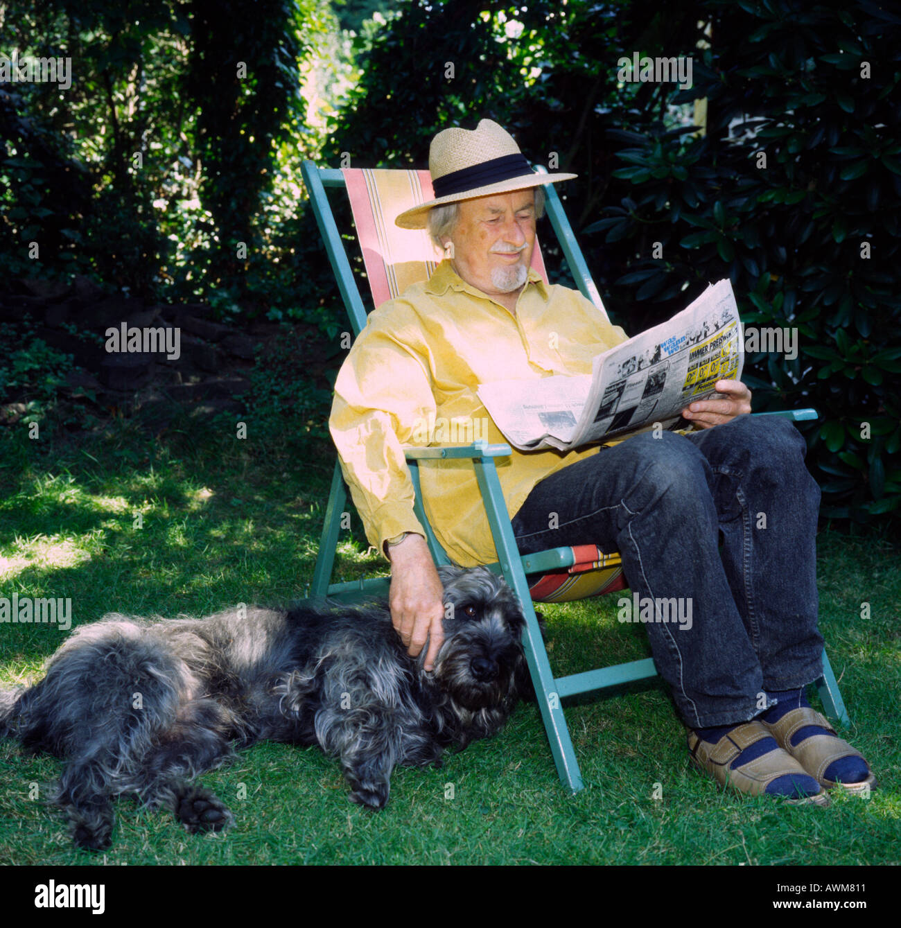 Senior man sitting with dog and reading newspaper Stock Photo - Alamy