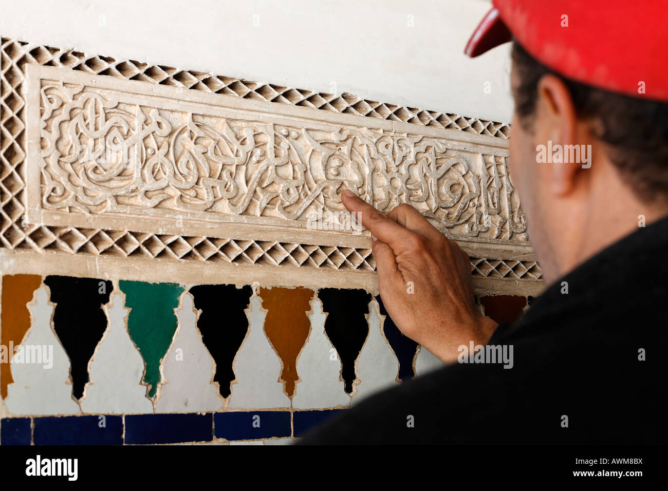 Guide explains Arabic letters of a stucco frieze, Palais de la Bahia, Medina, Marrakech, Morocco, Africa Stock Photo