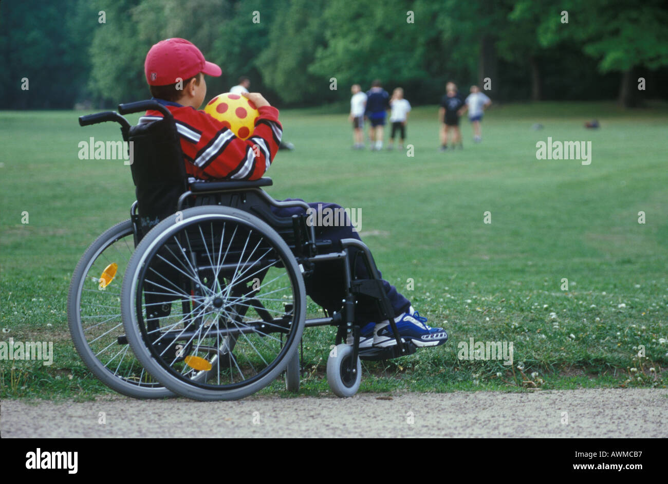 Handicapped child holding soccer ball in wheelchair Stock Photo