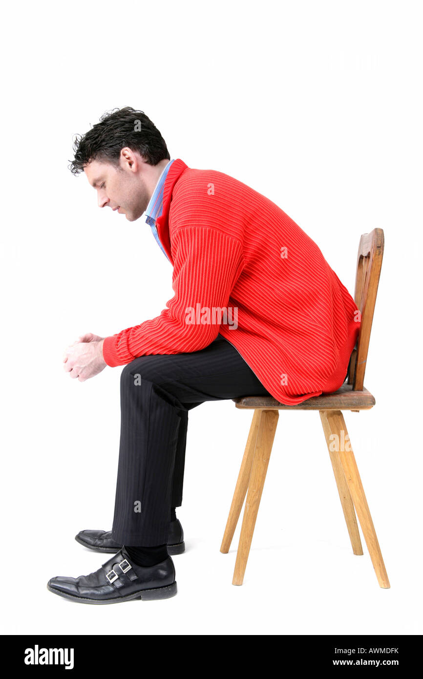 Man wearing red jacket sitting on an old wooden chair Stock Photo