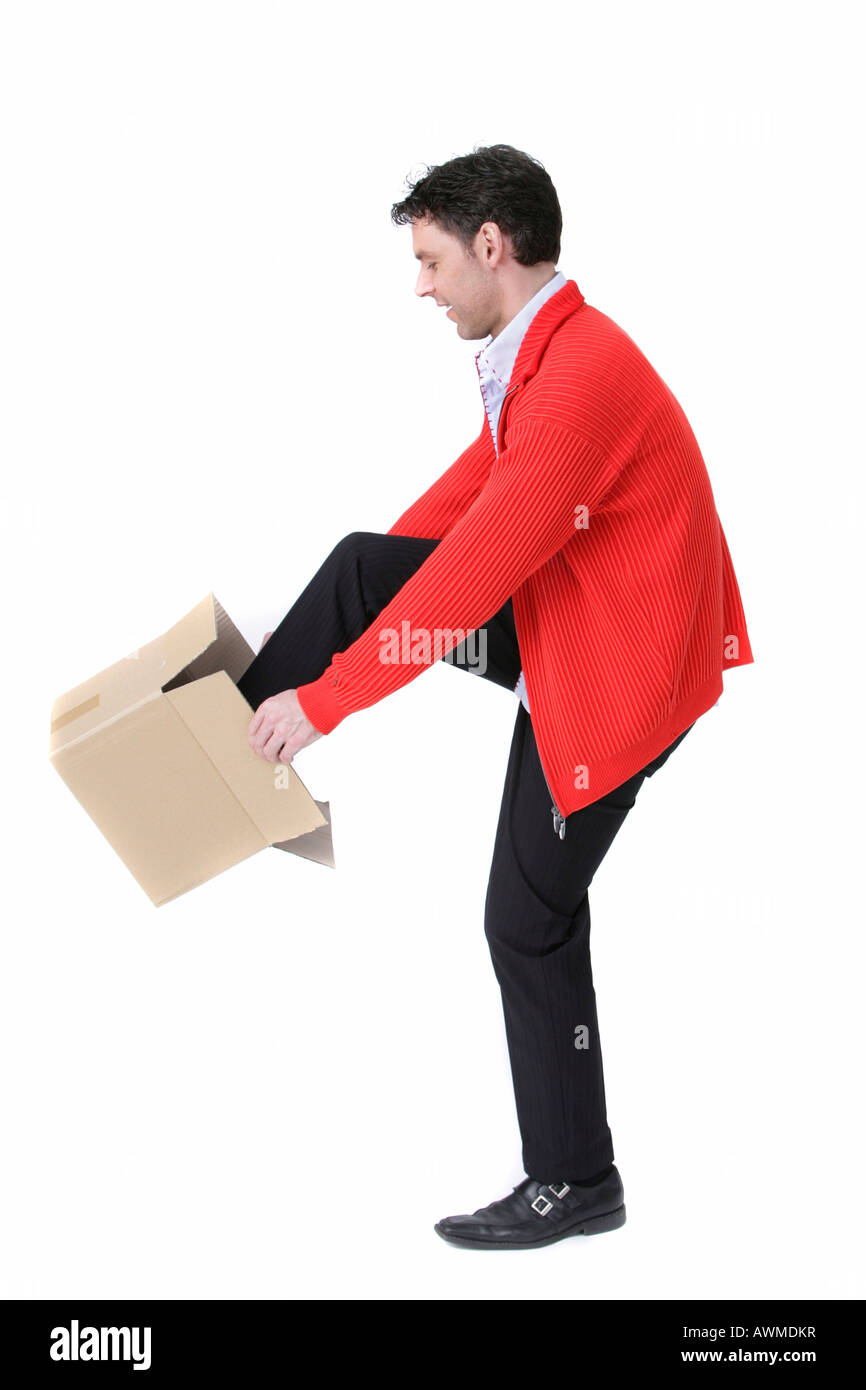 Man climbing into a small cardboard box Stock Photo
