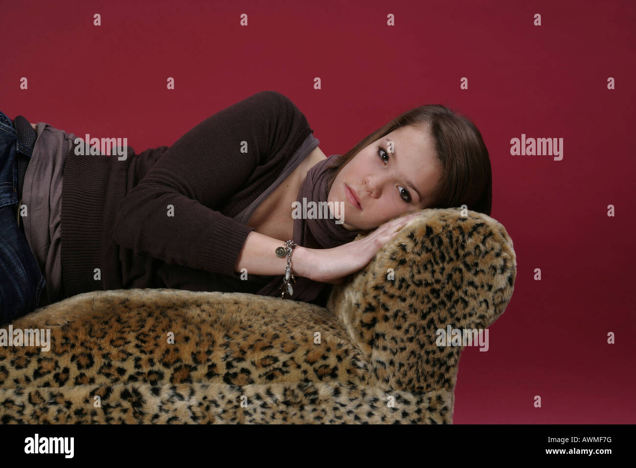 Portrait of a girl, pre-teen, early teens laying on a tiger-print sofa Stock Photo