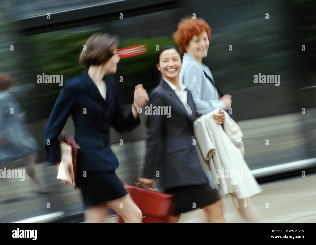 Three businesswomen walking in street, smiling, blurred Stock Photo - Alamy