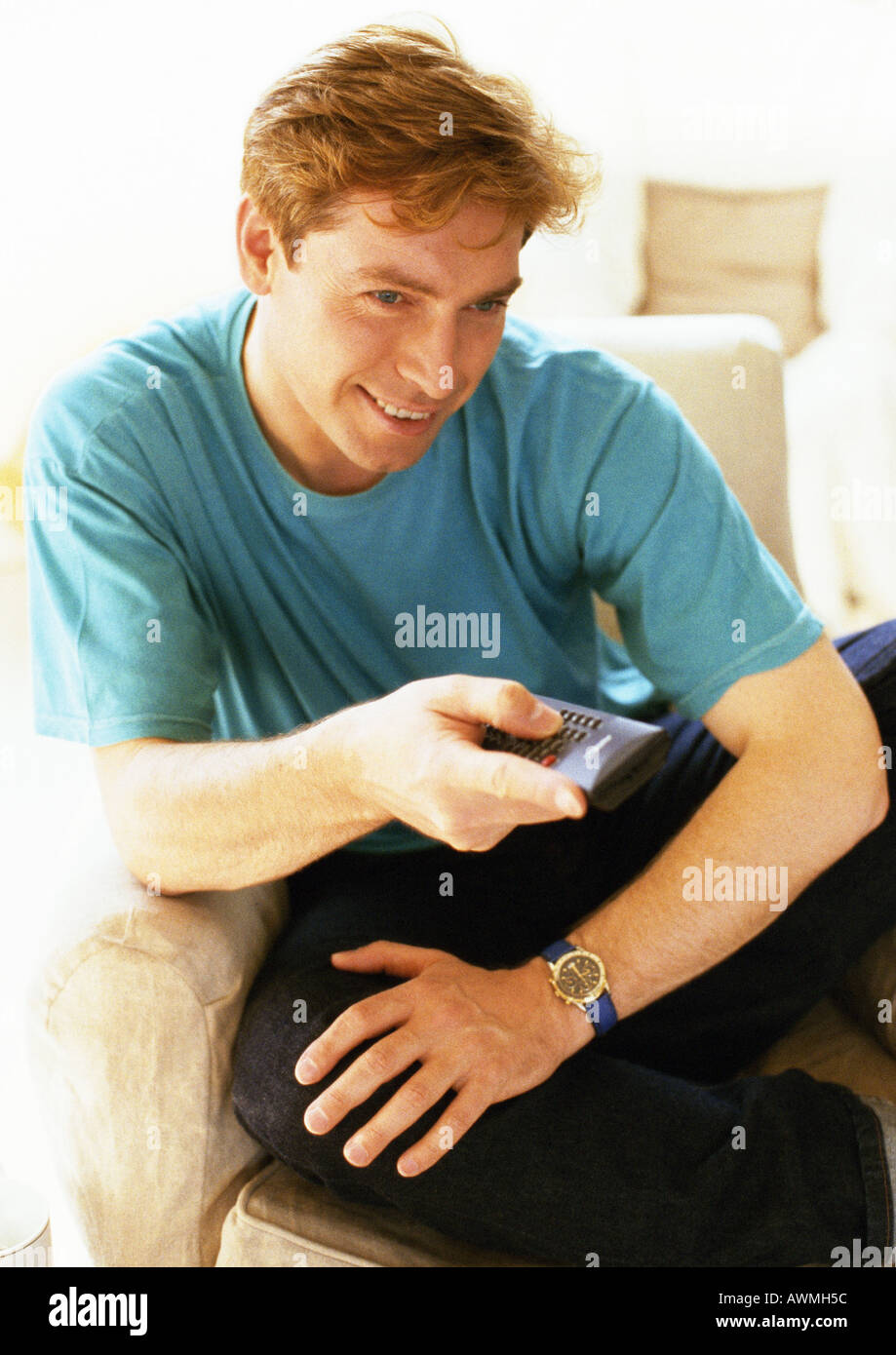 Man sitting, holding remote control, close-up Stock Photo