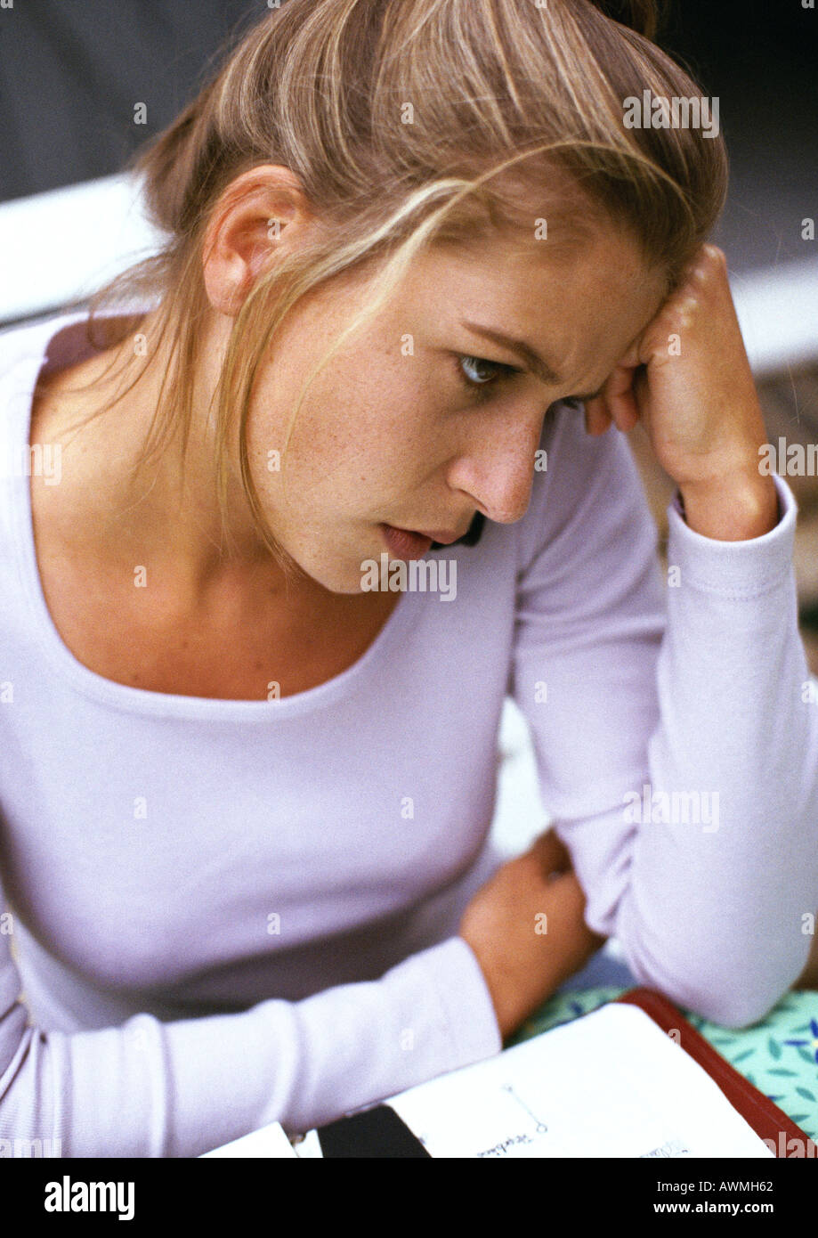 Woman sitting, head against hand, close-up, high angle view Stock Photo