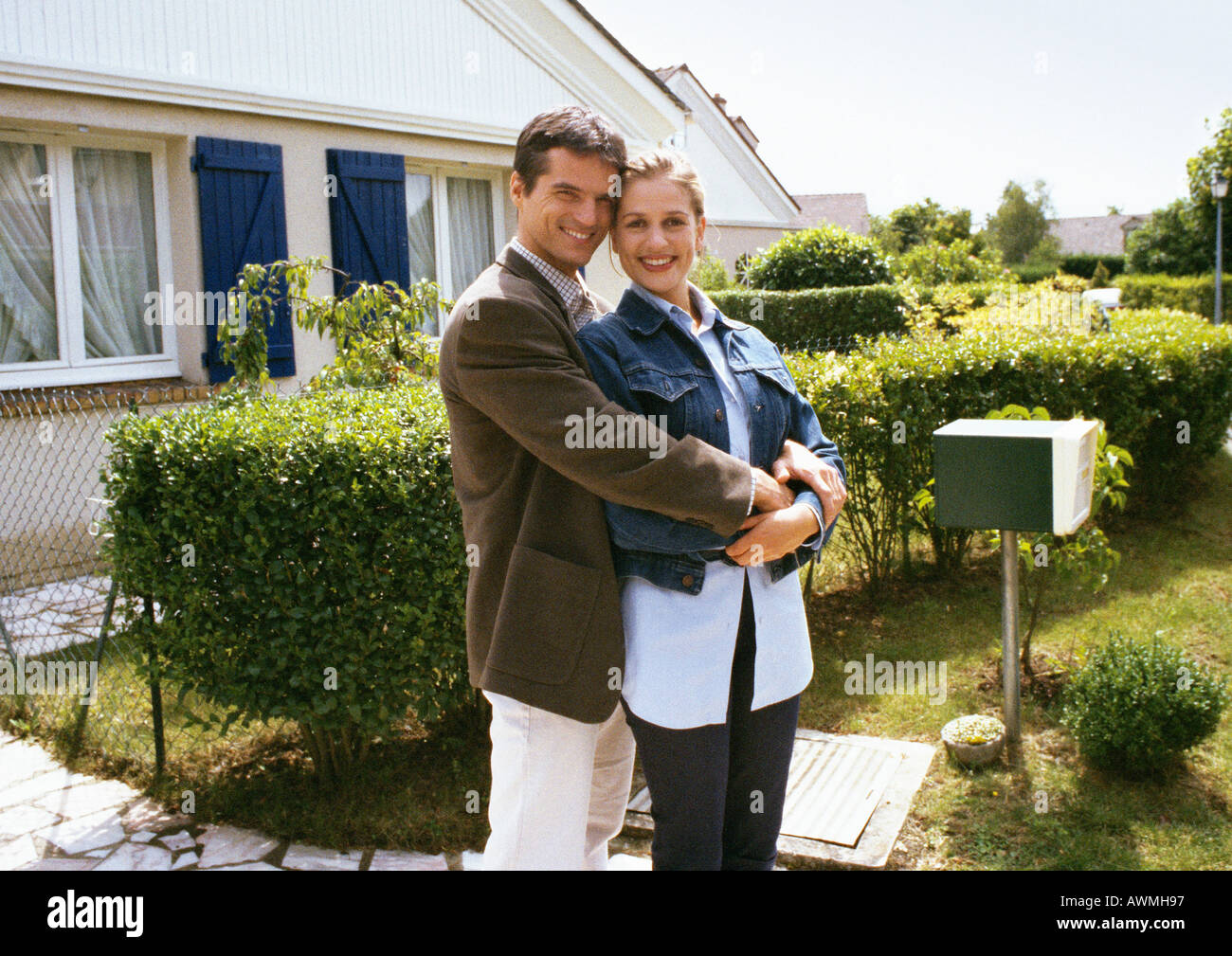 Couple standing in front of house, embracing Stock Photo