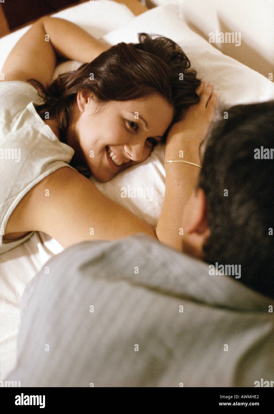 Woman lying on bed, looking at man in foreground Stock Photo