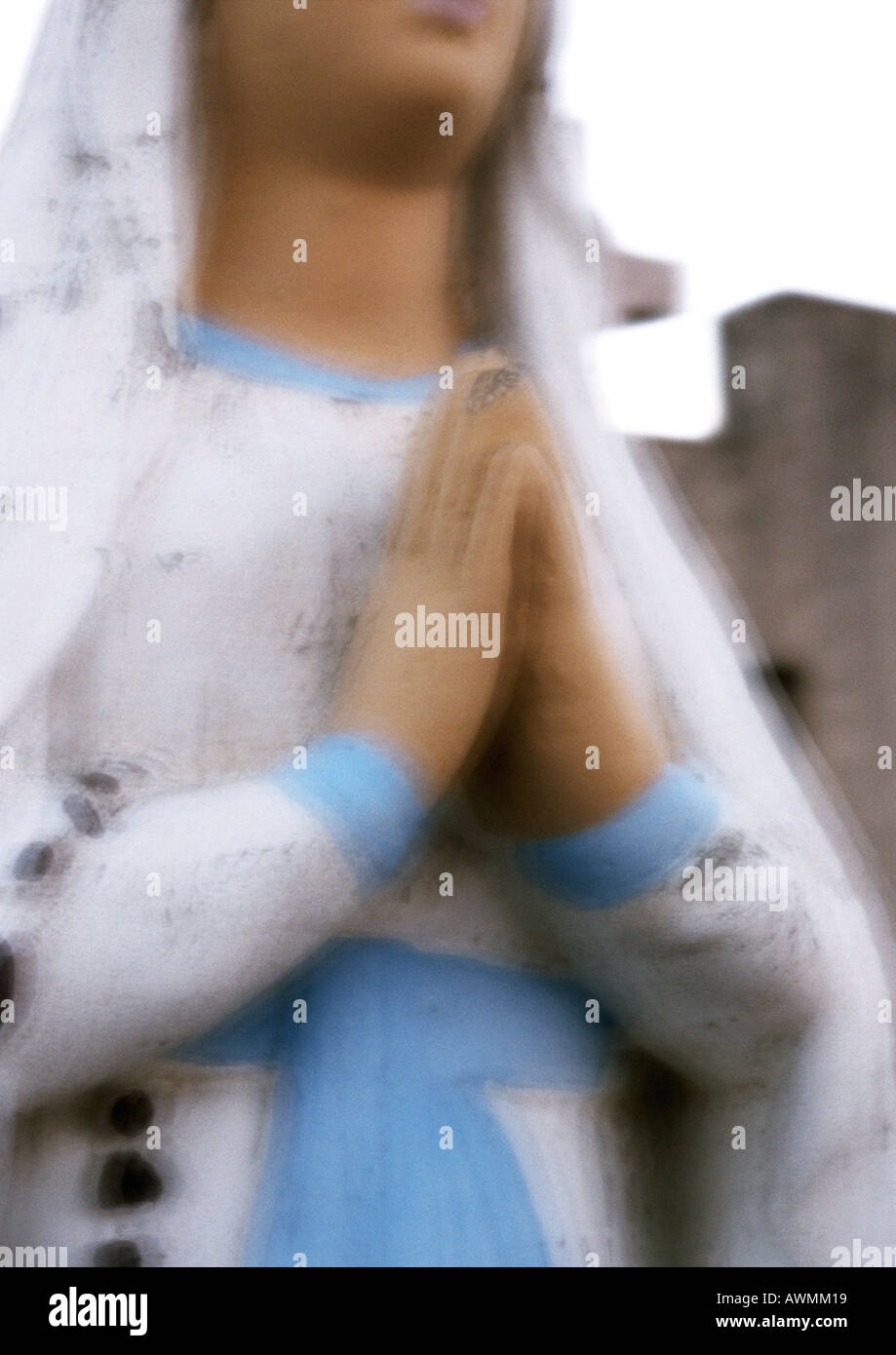 Statue of Virgin Mary with hands praying, partial view, blurred Stock Photo