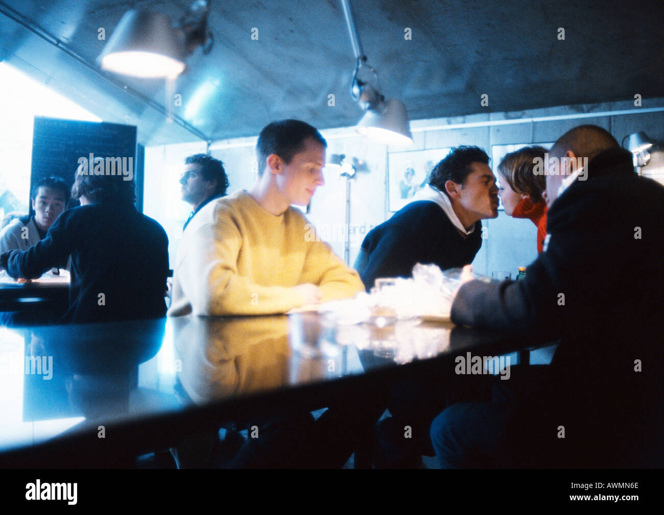 Young people sitting at table, couple kissing Stock Photo