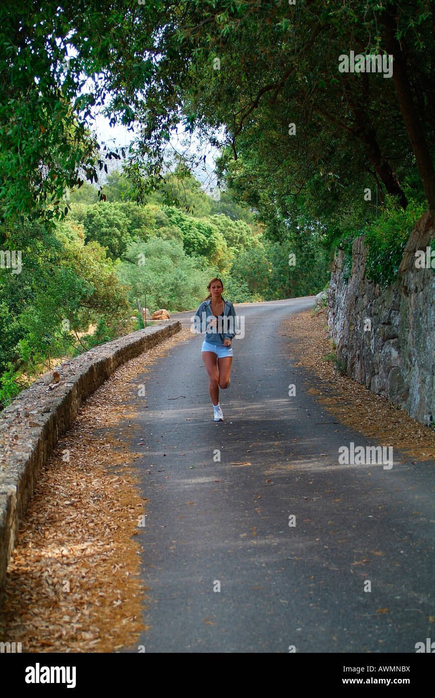 Young woman in sports clothing running on a forest road Stock Photo