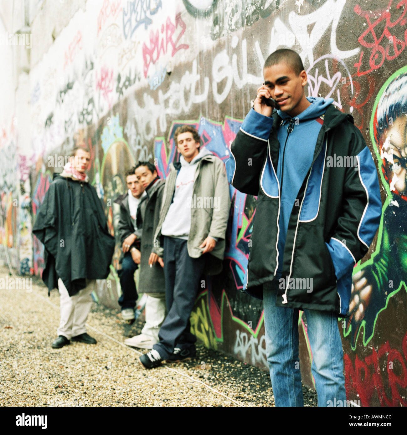 Five young men in front of wall covered in graffiti Stock Photo