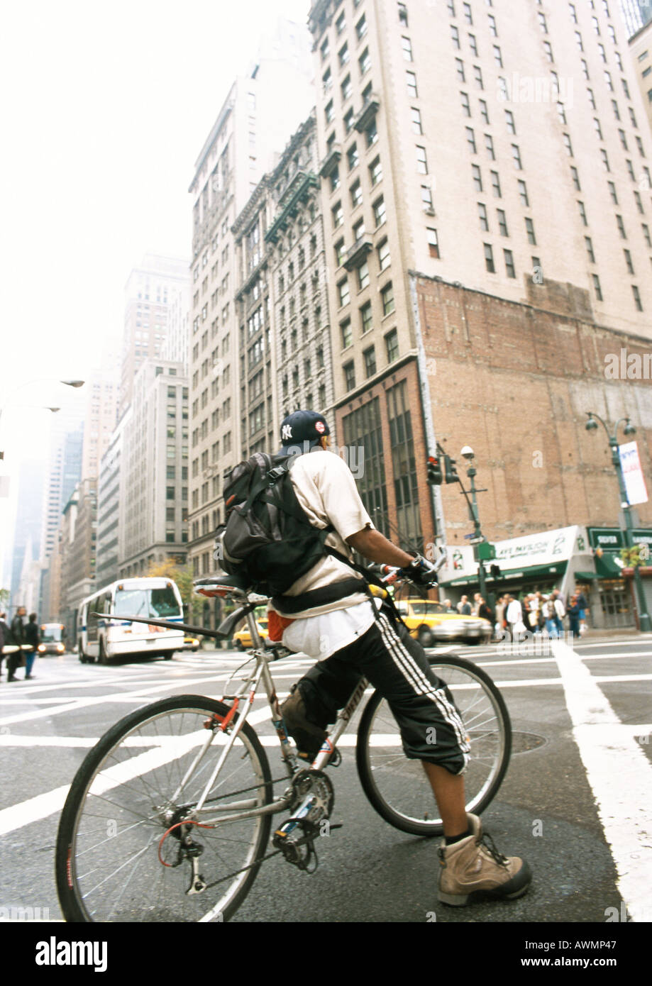 Man riding bike in street, buildings in background Stock Photo