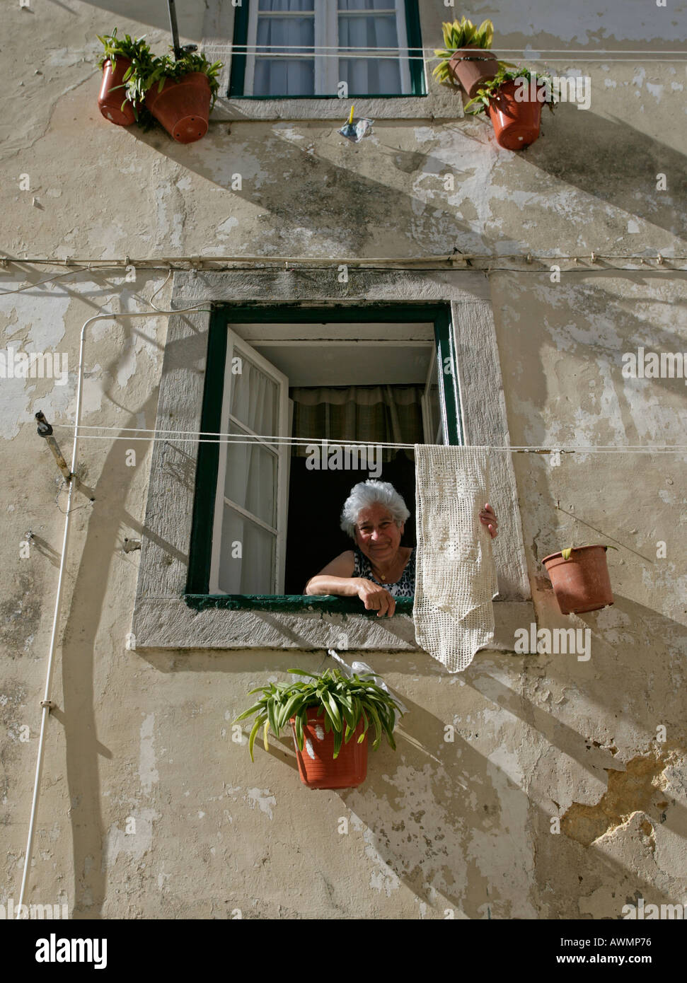 A woman hangs laundry out to dry outside her second story window in Sintra Portugal Stock Photo