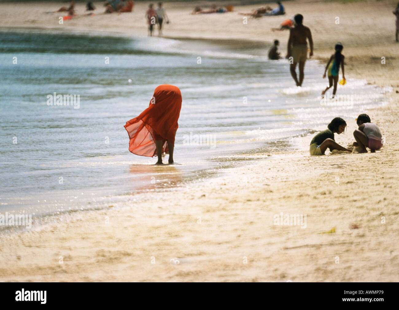 People on beach, woman bending over, ankledeep in water Stock Photo Alamy