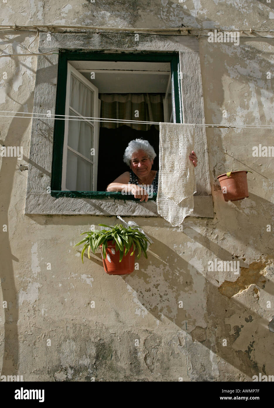A woman hangs laundry out to dry outside her second story window in Sintra Portugal. Stock Photo