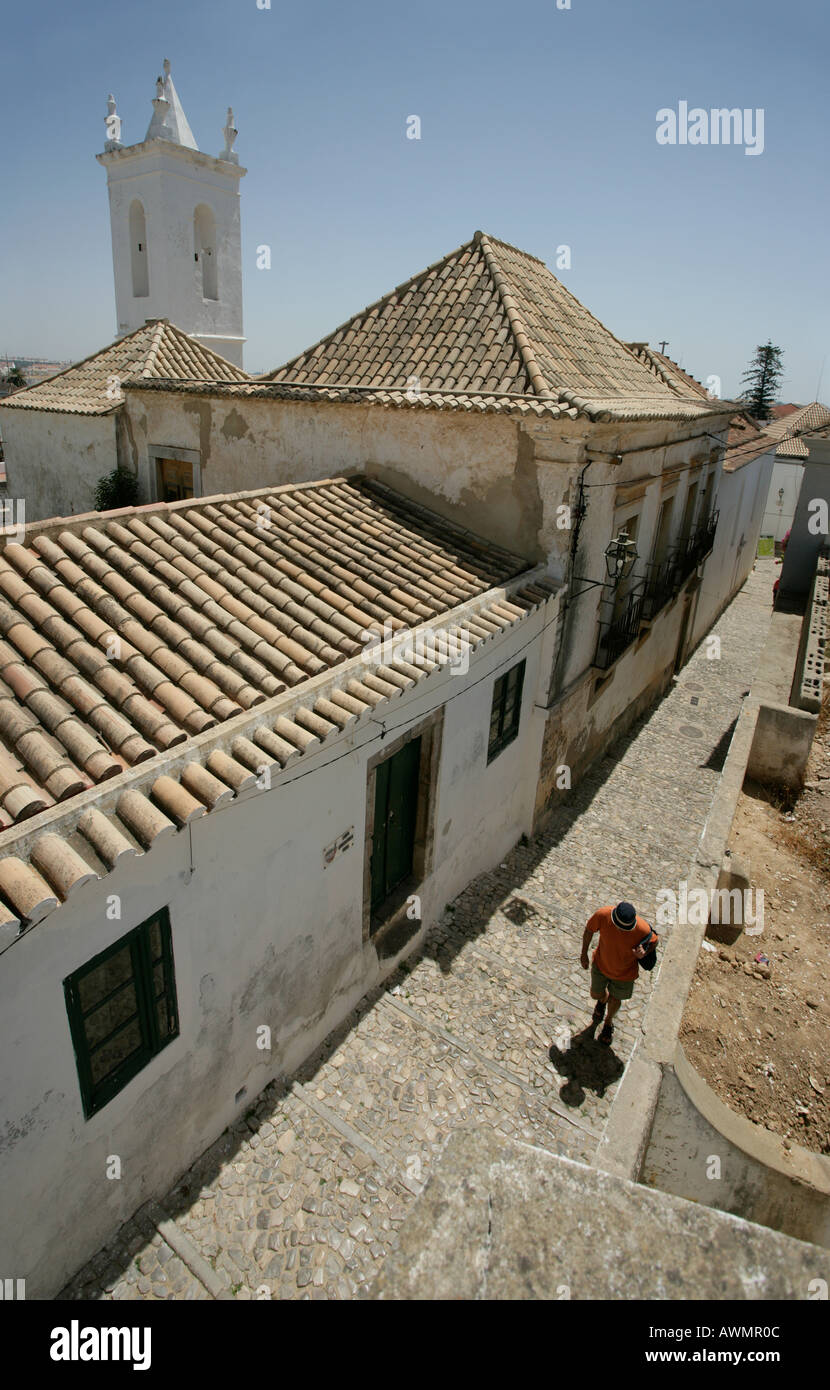 A narrow alley homes and a church spire in the coastal village of Tavira Tavira is on Portugal's Algarve coast. Stock Photo