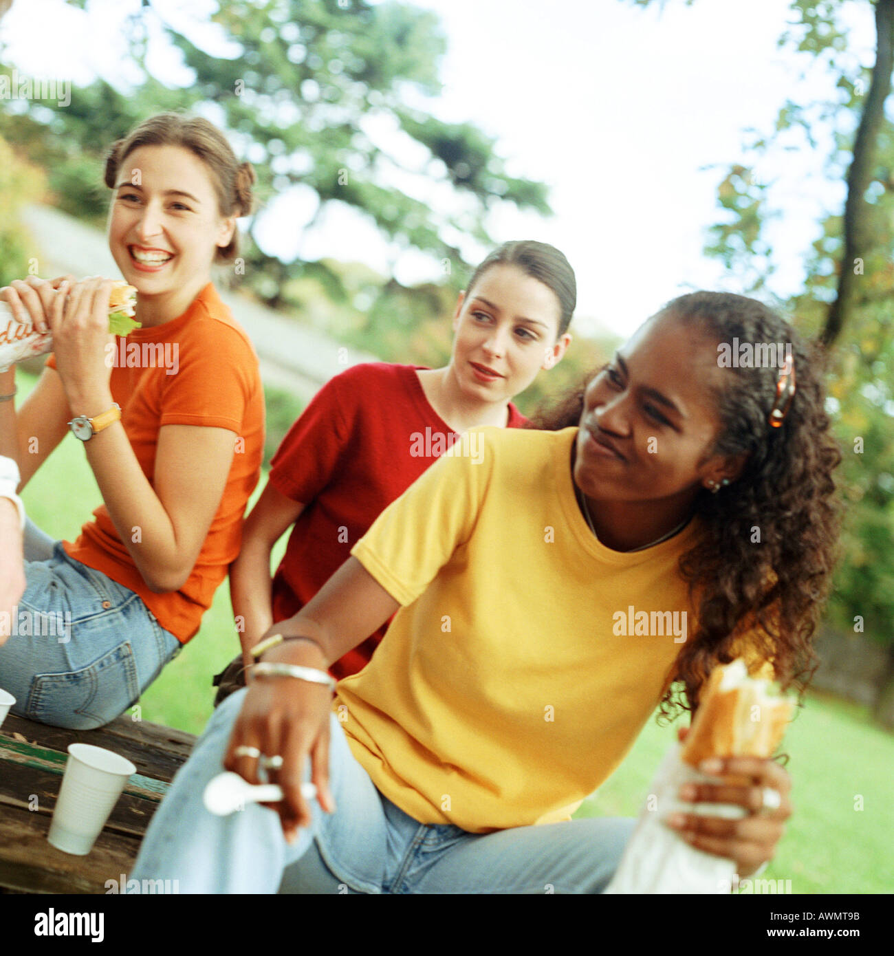 Young women eating sandwiches together outside Stock Photo