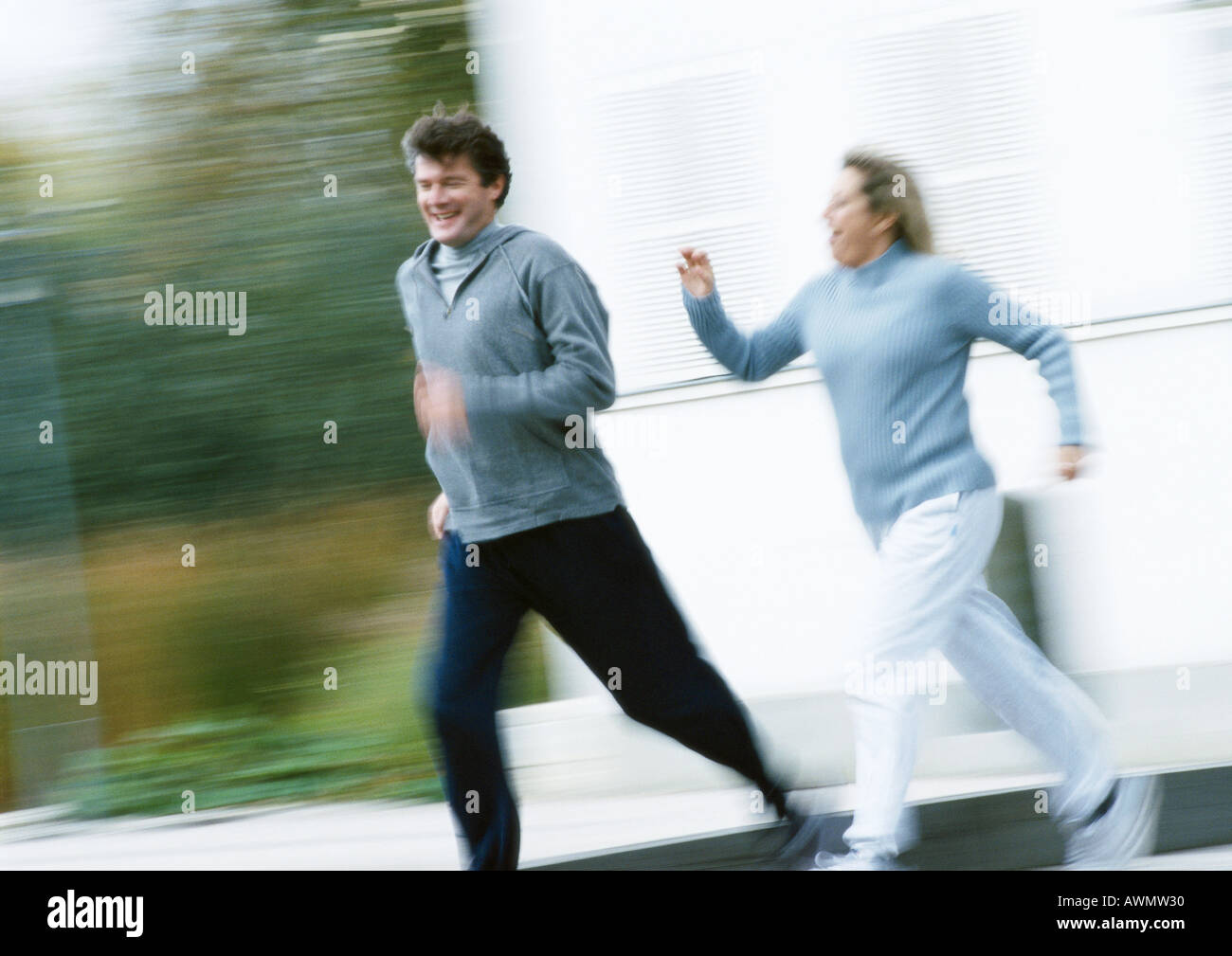Man and woman jogging together outside, blurred Stock Photo