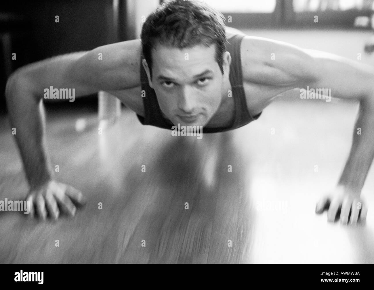 Man doing push up, looking at camera, blurred, black and white. Stock Photo