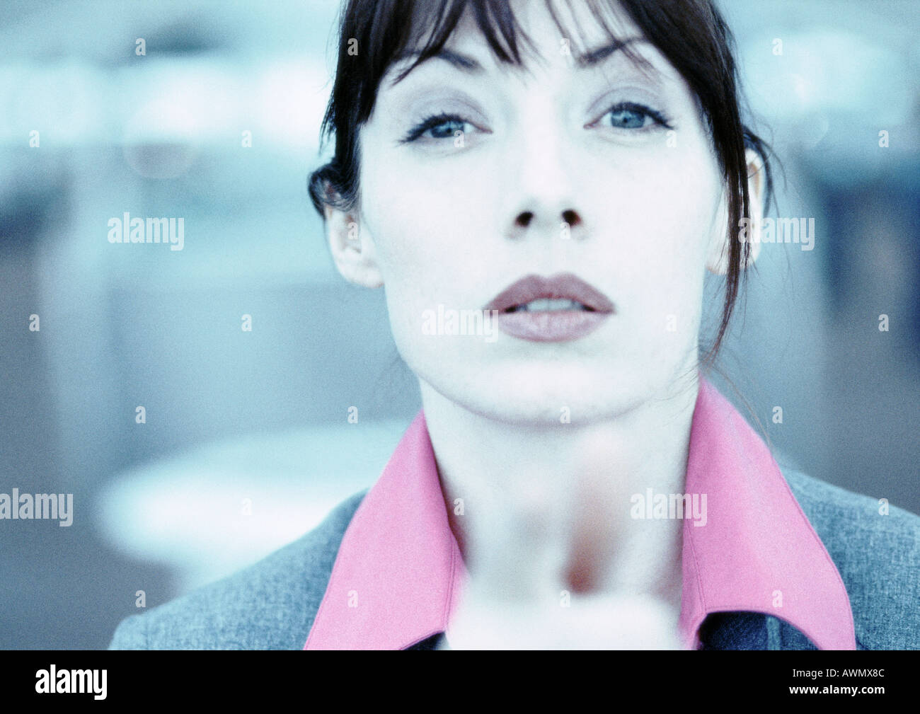 Businesswoman looking and pointing at camera, fingers blurred in foreground, close-up, cool toned. Stock Photo