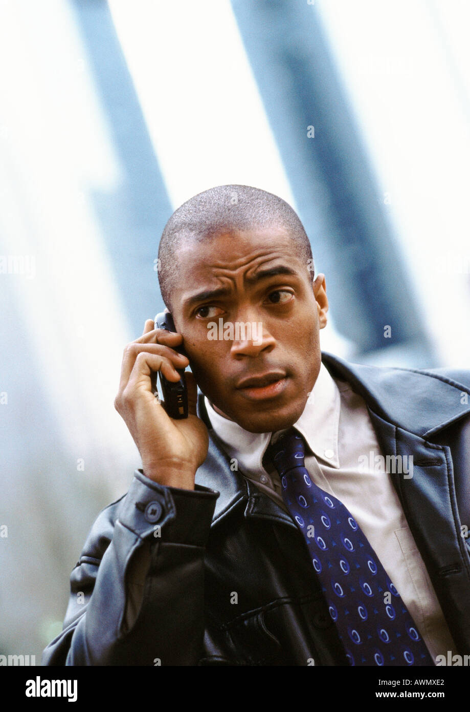 Businessman using cellular phone and furrowing brow, portrait. Stock Photo