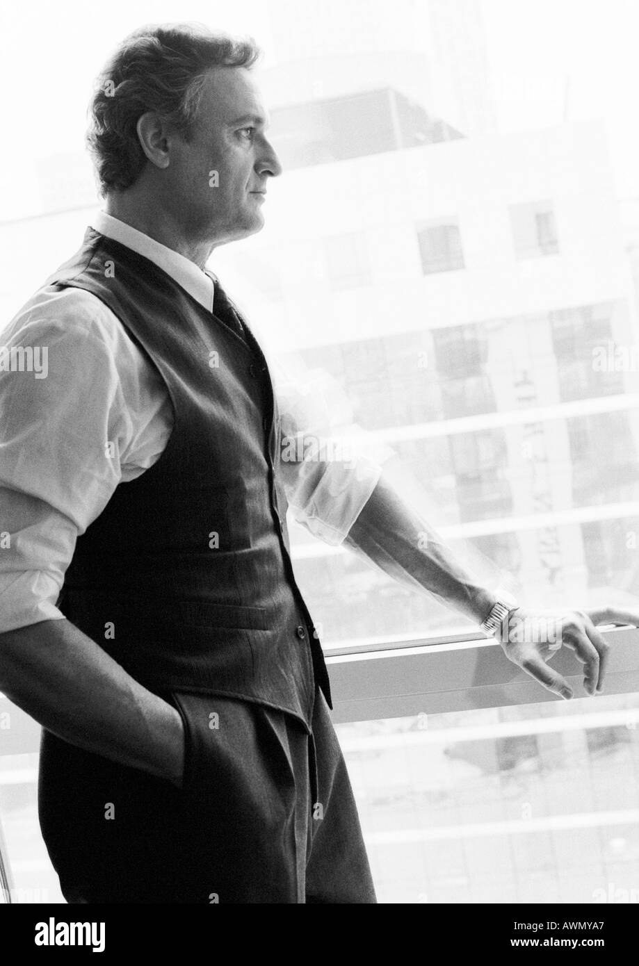 Businessman standing next to window looking out, side view, b&w. Stock Photo