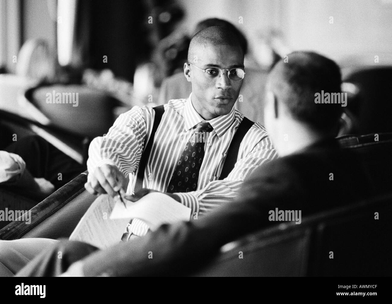 Businessmen sitting, discussing document, b&w. Stock Photo