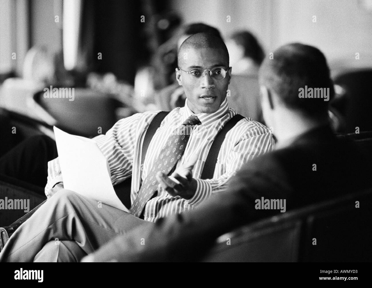 Businessmen sitting, discussing document, b&w. Stock Photo