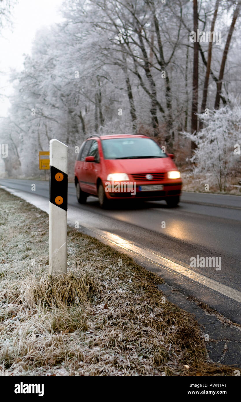 Winter traffic, car driving by reflector post with headlights on, Hesse