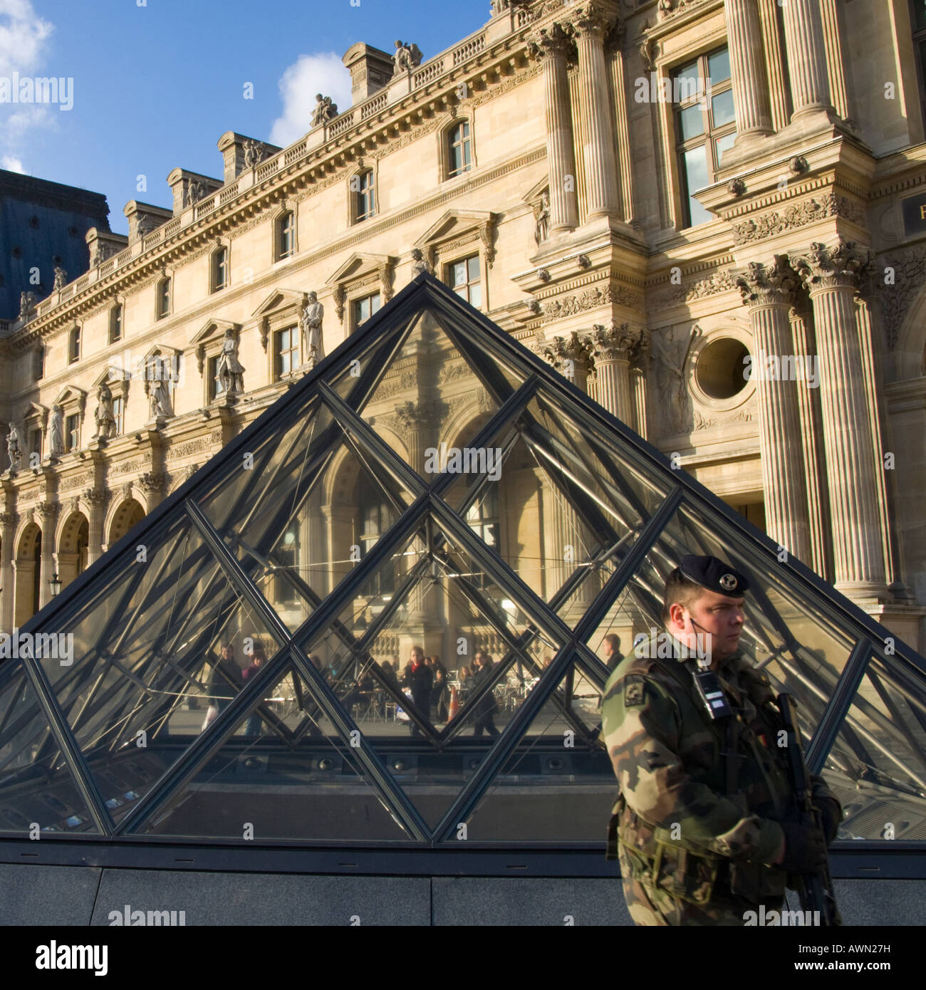 France Paris 1 Le Louvre esplanade small glass pyramide view with armed soldier patroling and facade in bkgd Stock Photo
