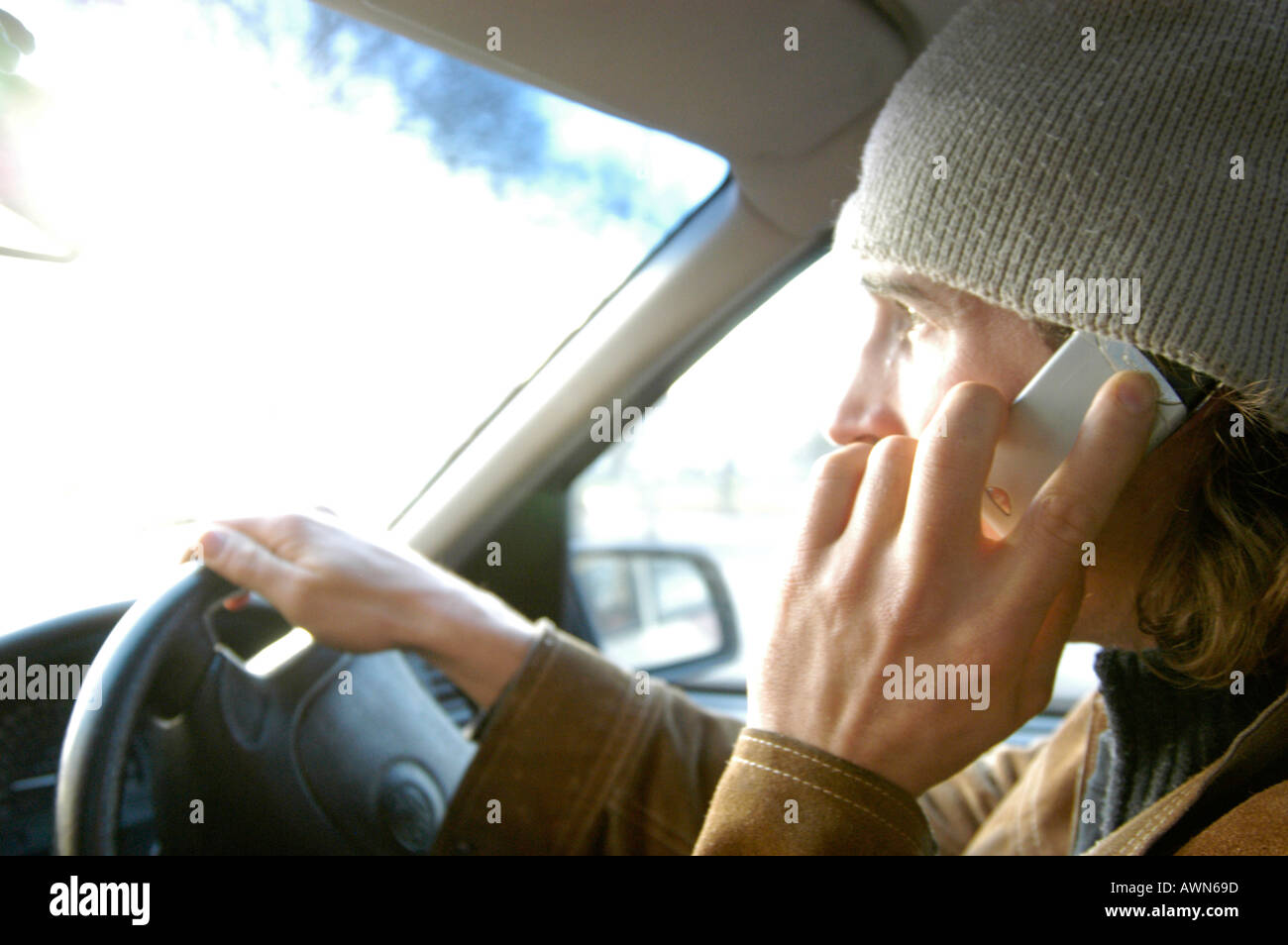 Young man illegally driving car while talking on mobile phone, England, UK Stock Photo