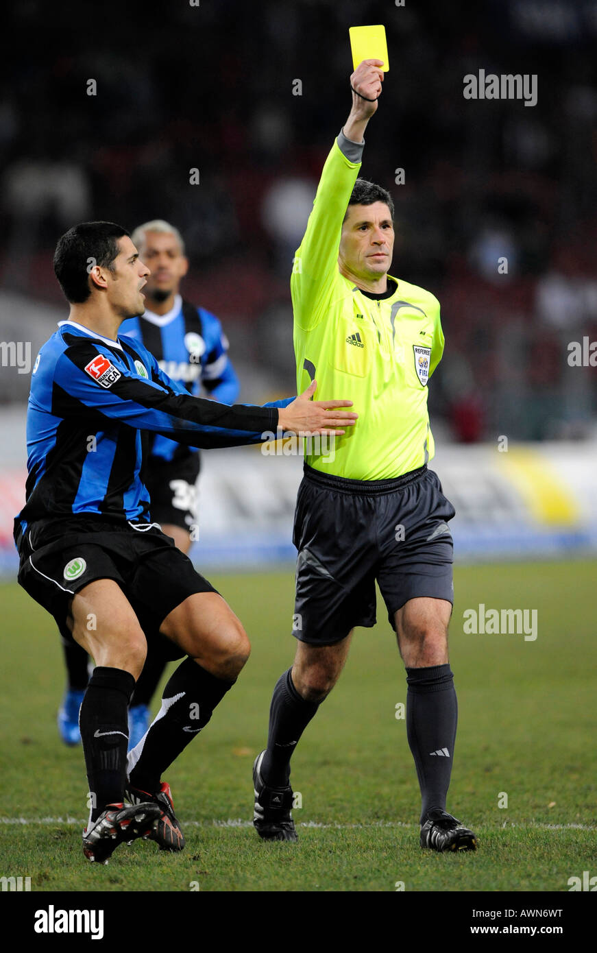 Referee Dr. Markus MERK showing yellow card while Ricardo COSTA VfL Wolfsburg is objecting Stock Photo