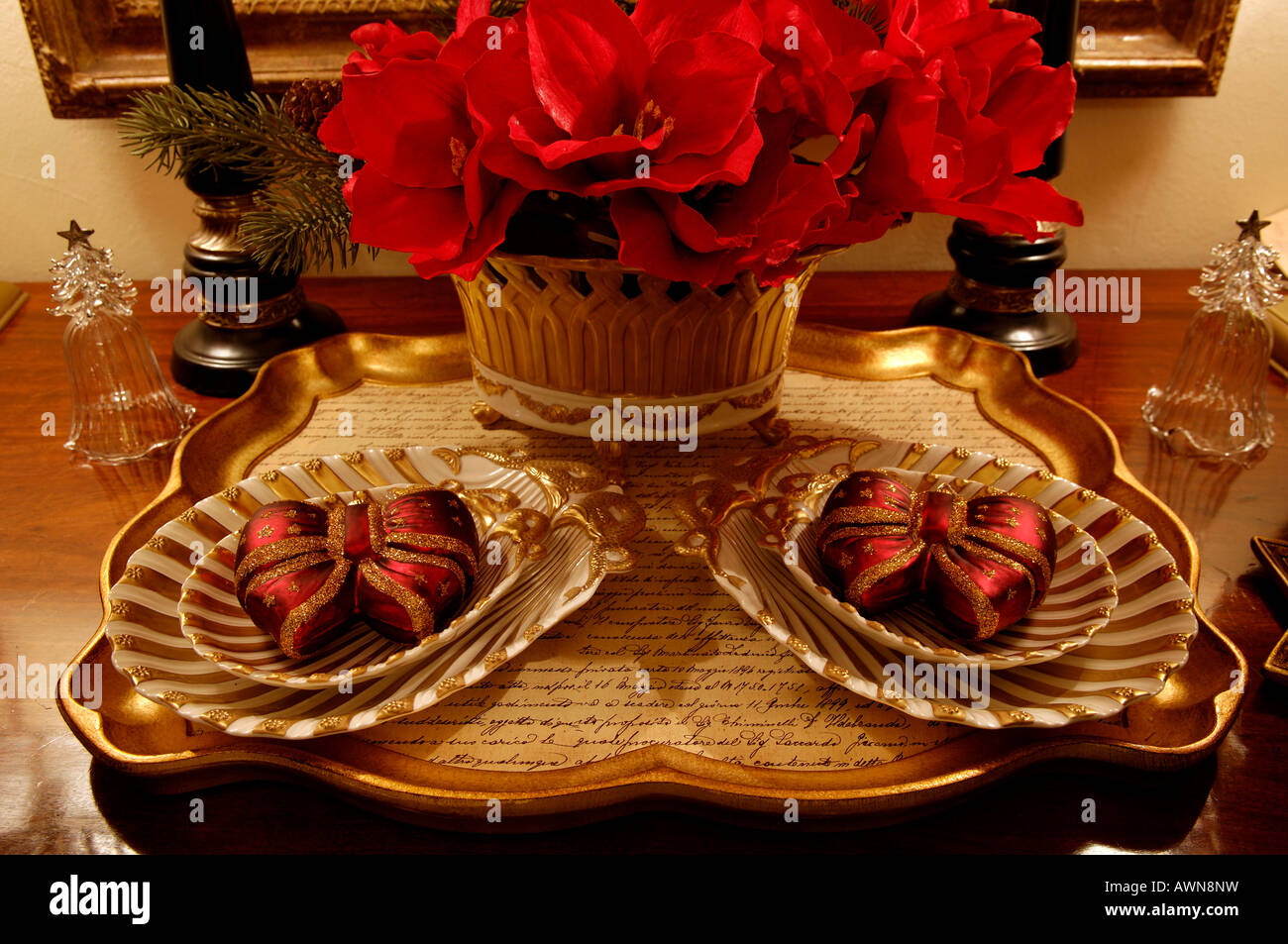 Christmas decorations on a tray with red artificial flowers in vase Stock Photo