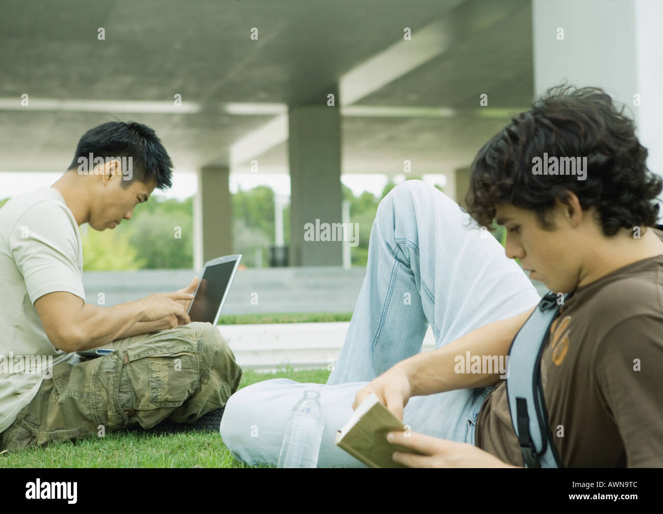 Two male college students sitting on grass, studying Stock Photo