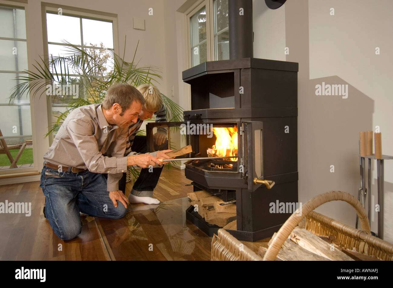 Man and boy firing an oven with wood, low-energy house, Kleinmachnow, Brandenburg, Germany Stock Photo