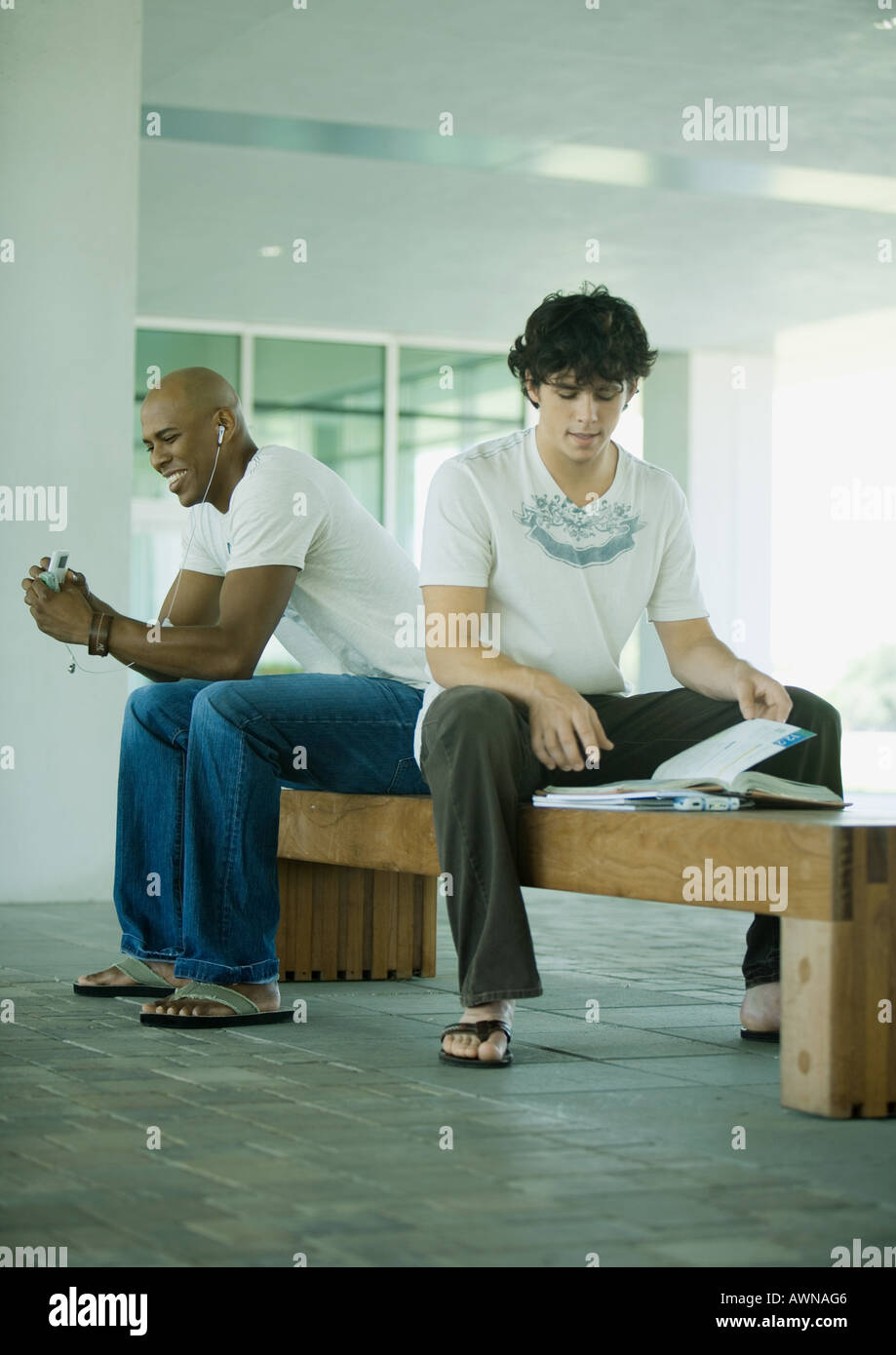 Male students sitting on bench on campus Stock Photo