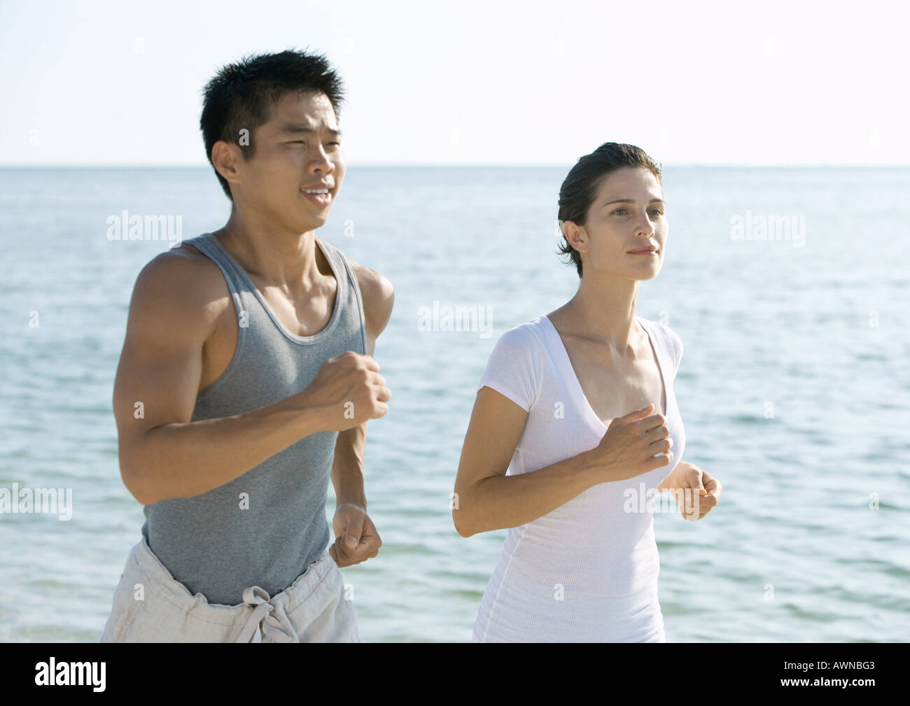Couple running next to ocean Stock Photo