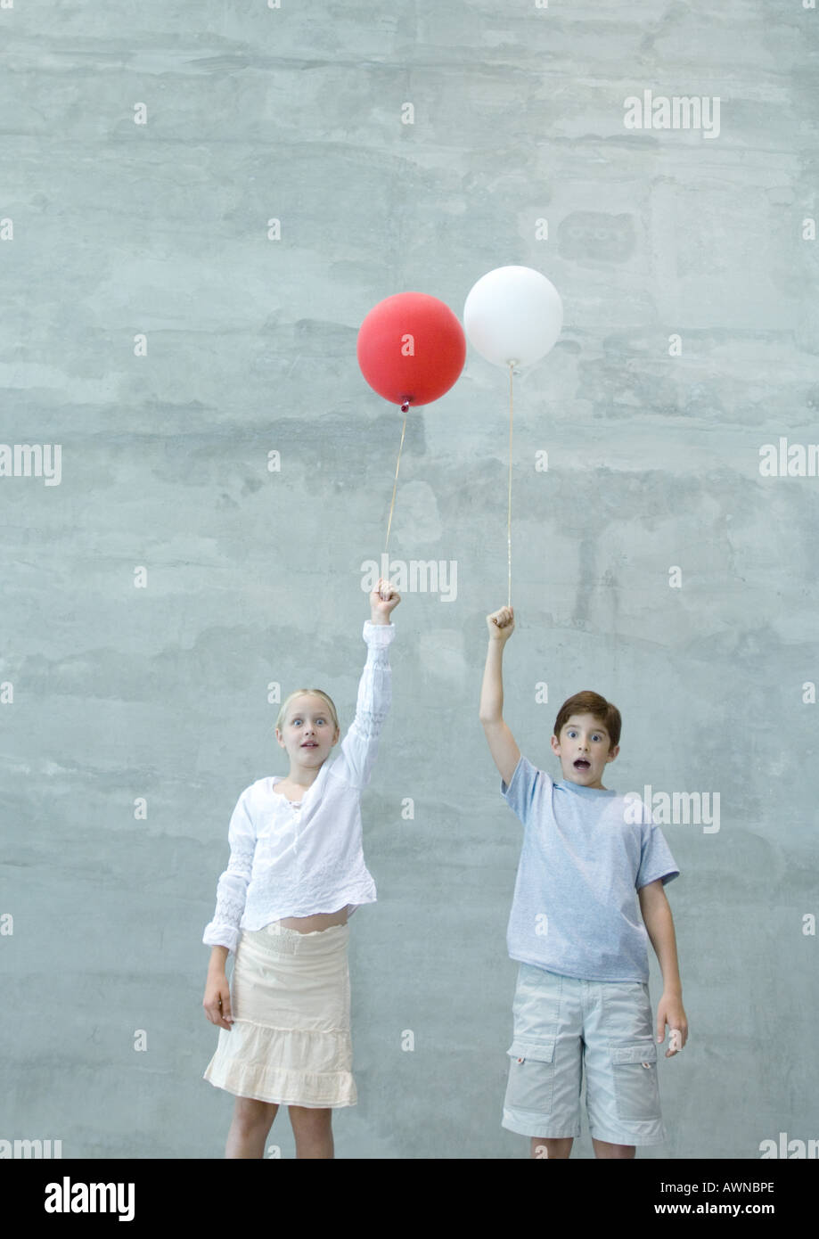 Two children holding balloons, making faces Stock Photo