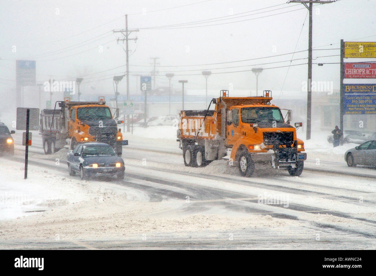 City snow removal trucks keep roads open during a winter snow storm in Michigan Stock Photo