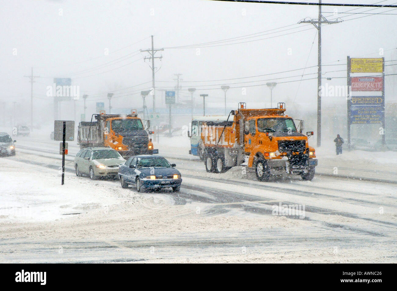 City snow removal trucks keep roads open during a winter snow storm in Michigan Stock Photo