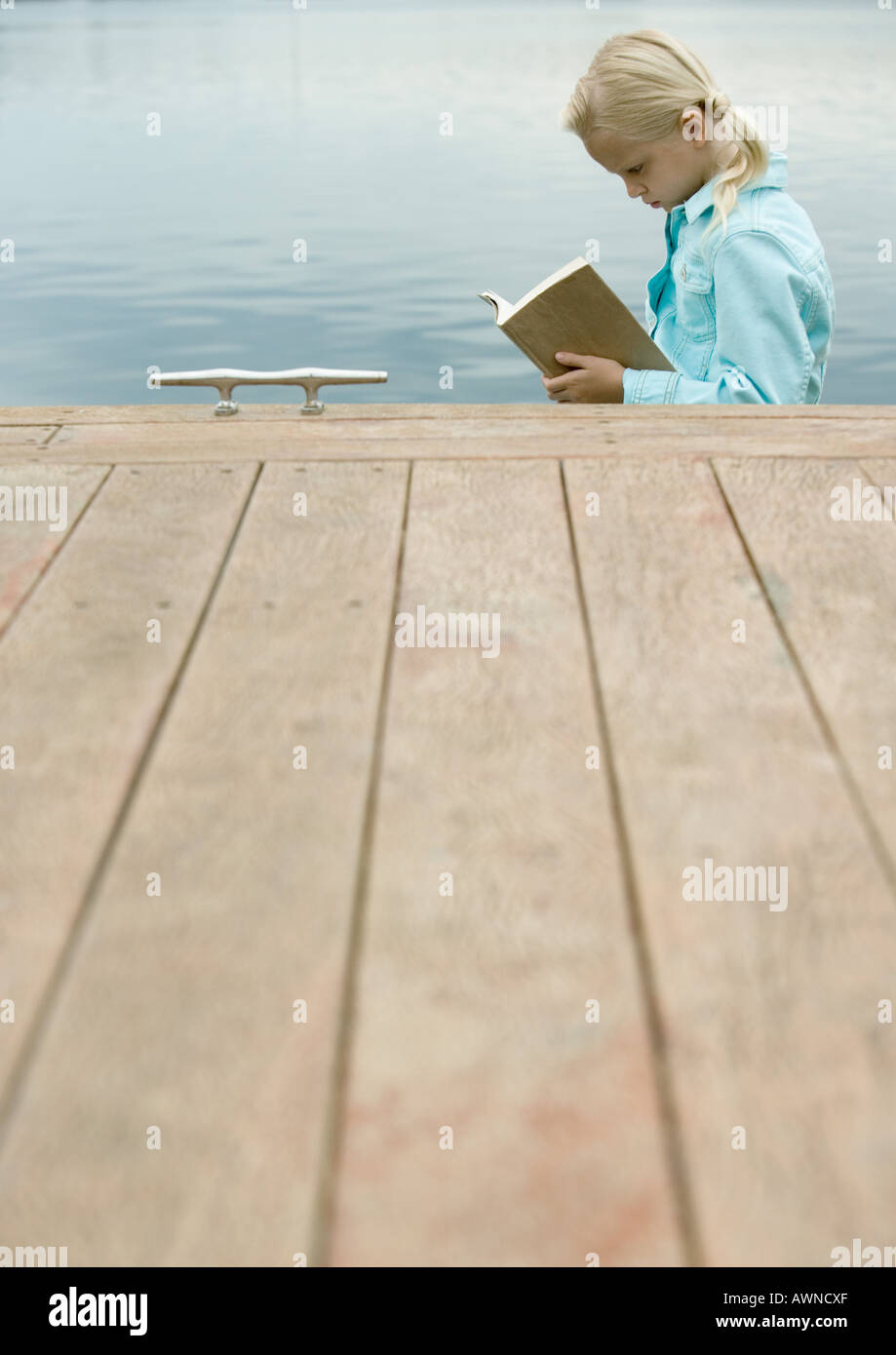 Girl reading book by water Stock Photo