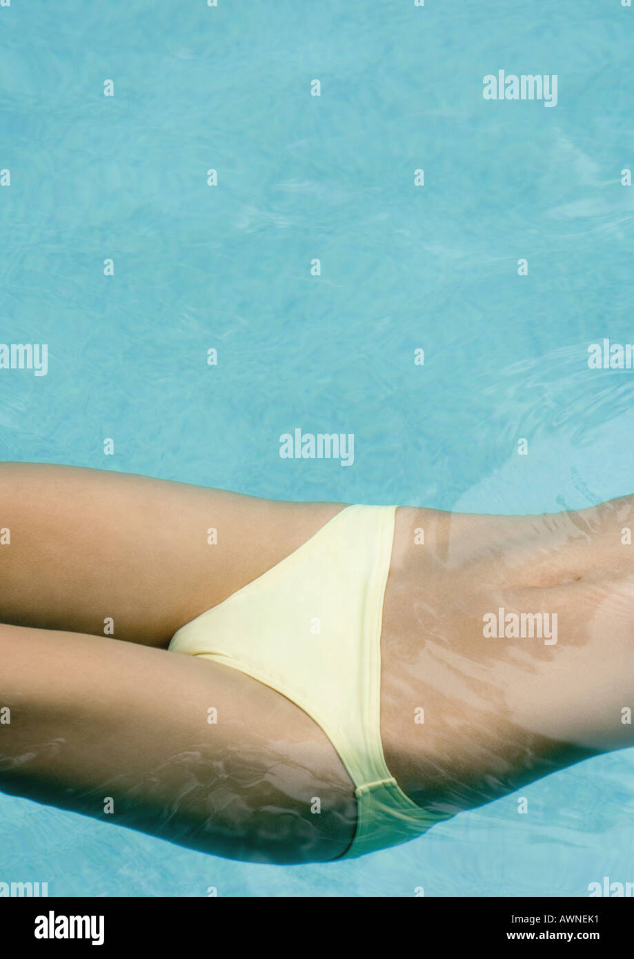 Woman floating in pool, close-up of mid section Stock Photo
