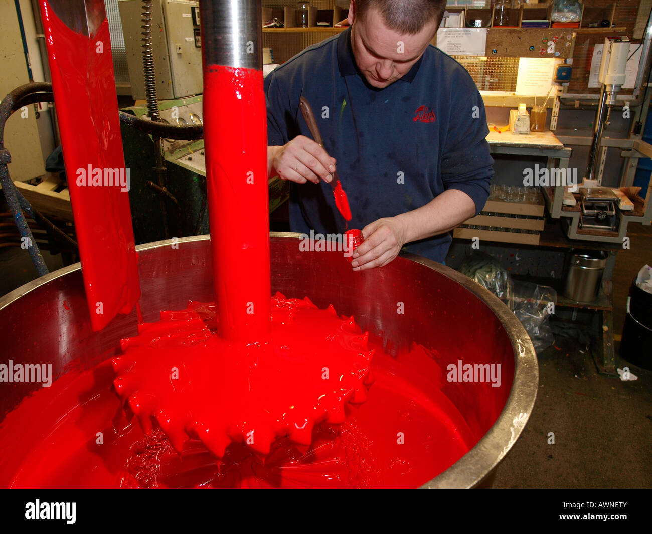 Man taking a bright red acrylic paint sample to test viscosity after mixing at the Royal Talens paint factory Stock Photo