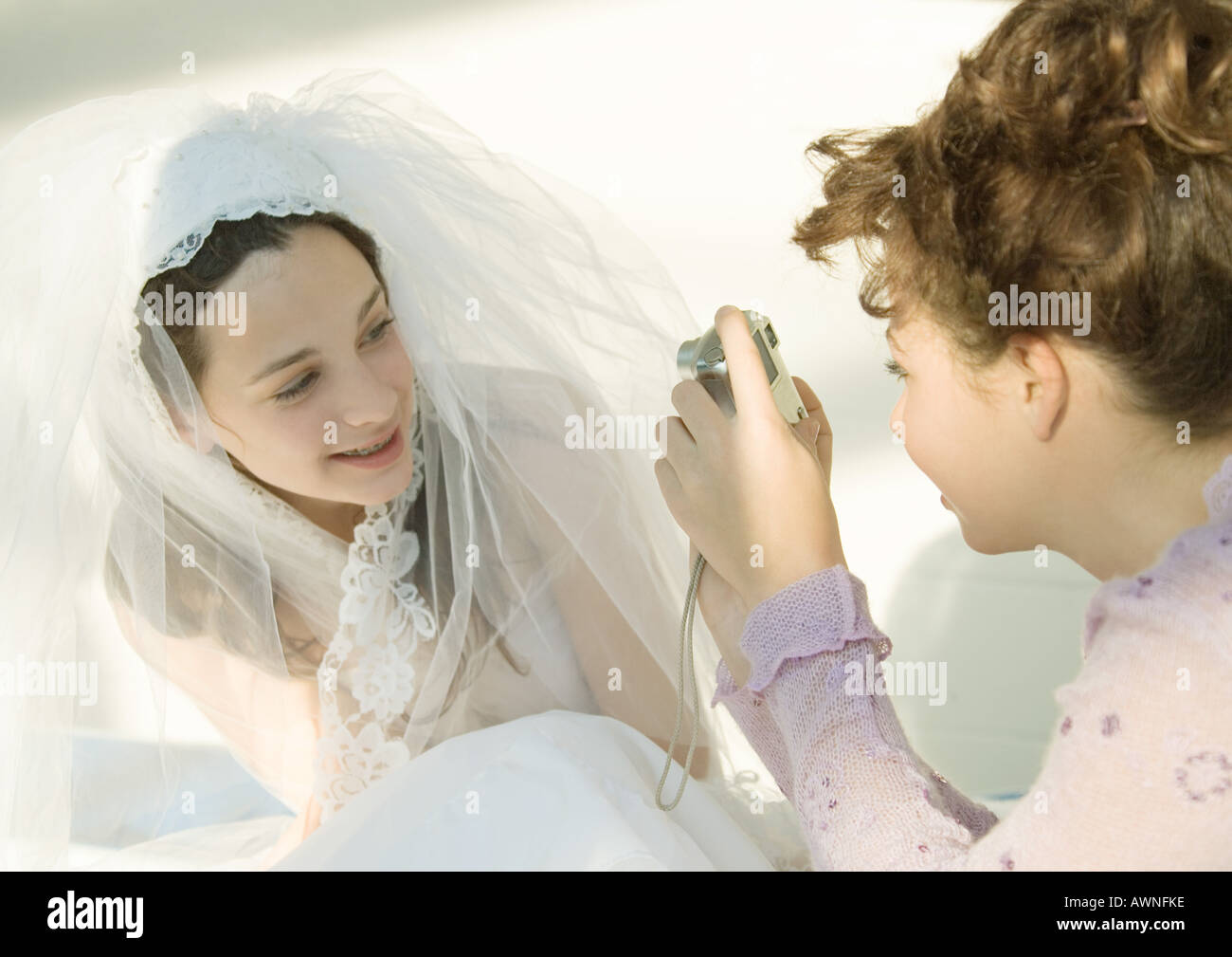 Preteen girl taking photo of friend dressed in wedding dress Stock Photo