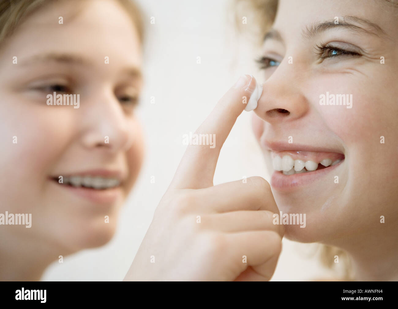 Girl putting lotion on friend's nose Stock Photo Alamy