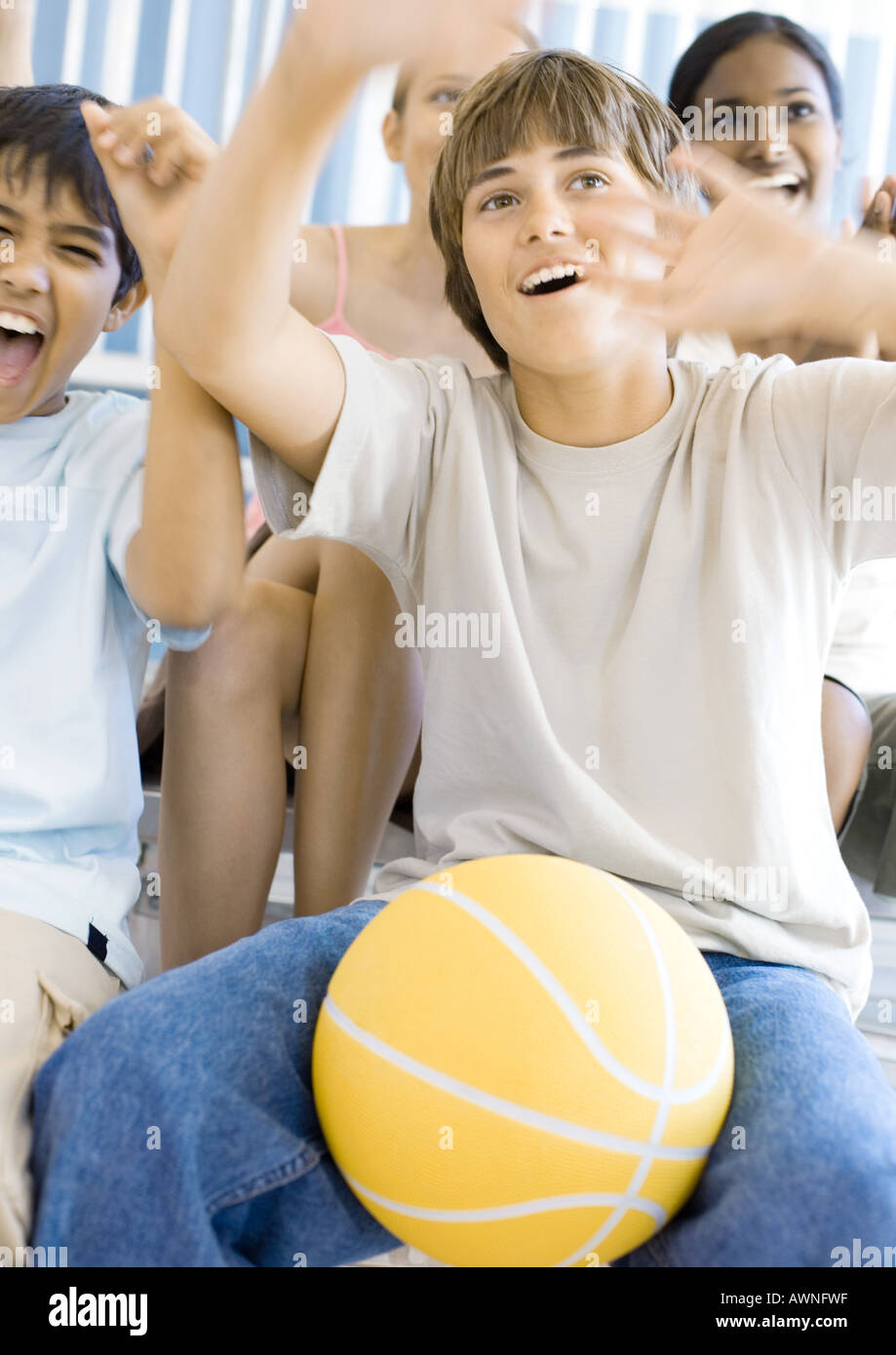 Group of high school students sitting with basketball, cheering Stock Photo