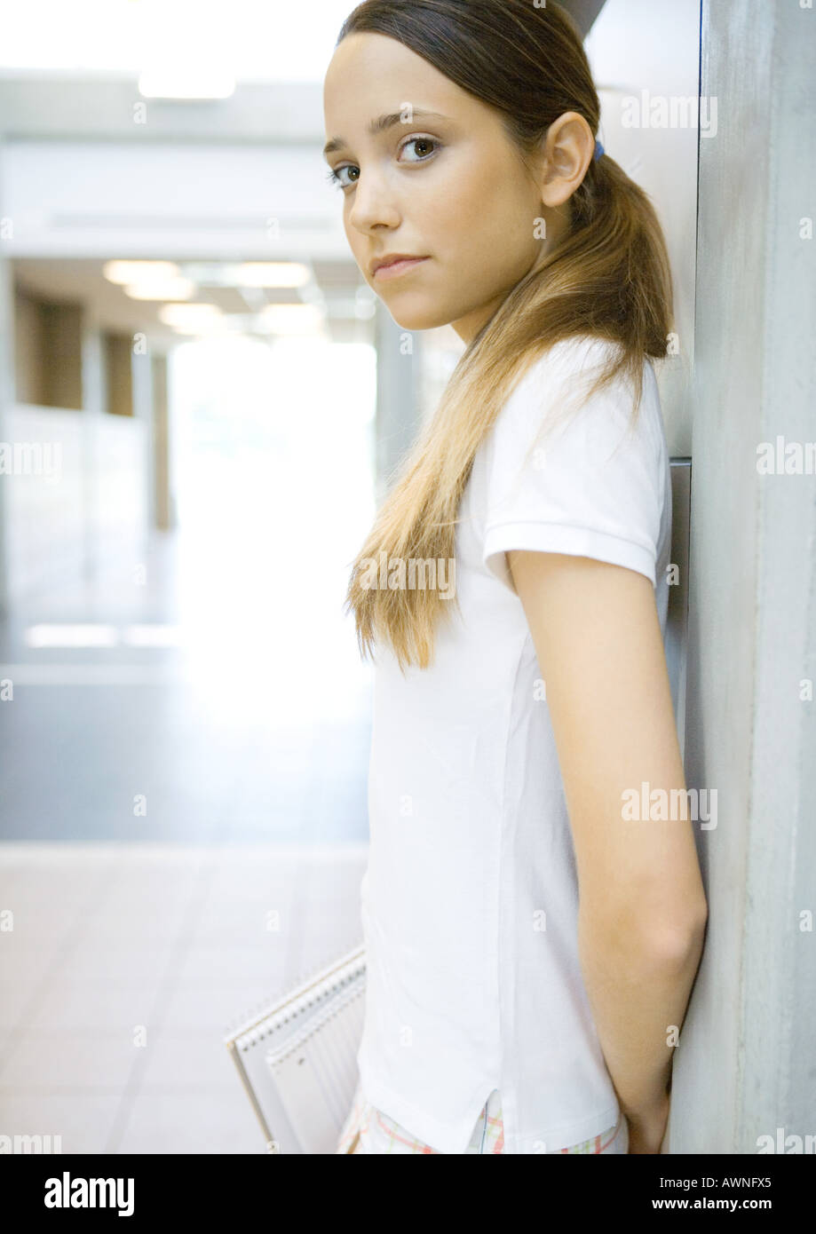 Teen girl leaning against wall, looking at camera Stock Photo