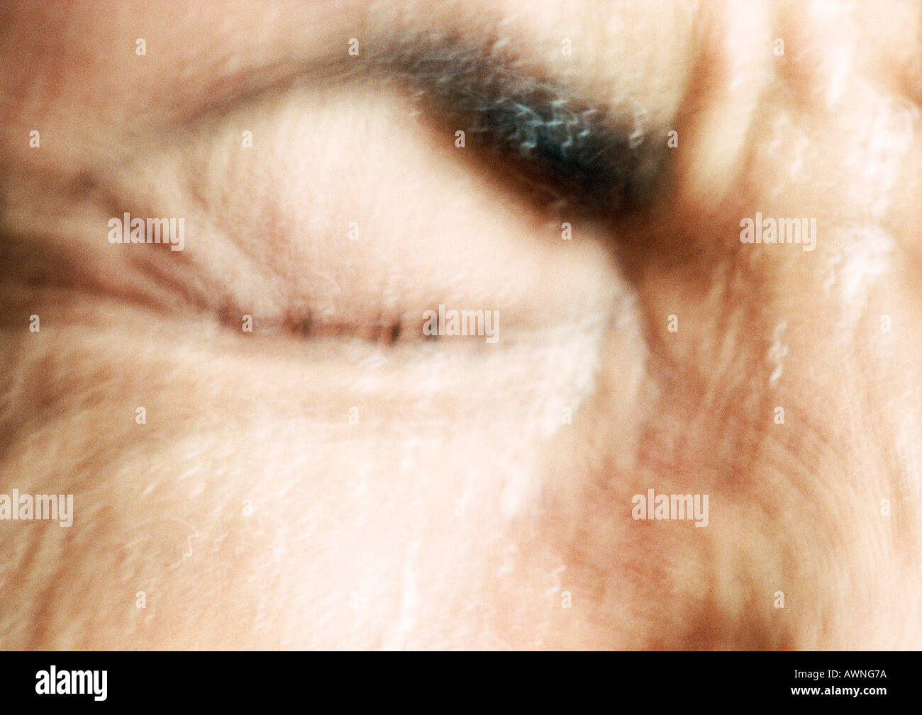 Partial view of woman's wrinkled face,  eye squeezed closed, blurred. Stock Photo